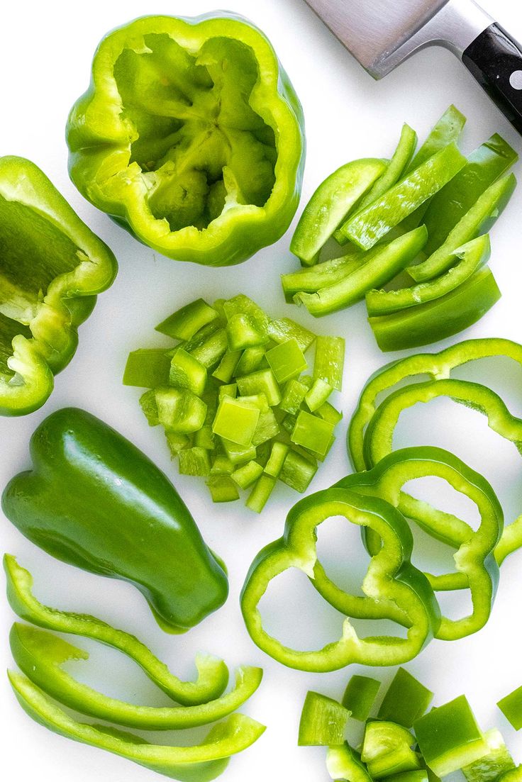 green peppers cut up on a cutting board next to a knife and pepper cutters