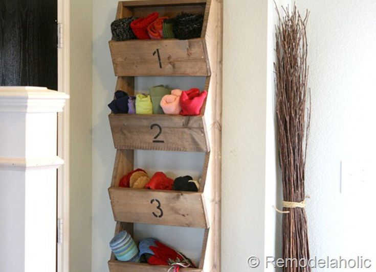 a wooden shelf filled with pairs of shoes next to a wall mounted vase and broom