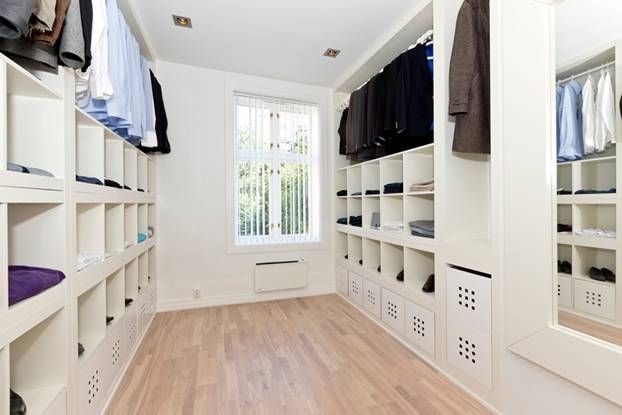 a large walk in closet with white shelves and drawers