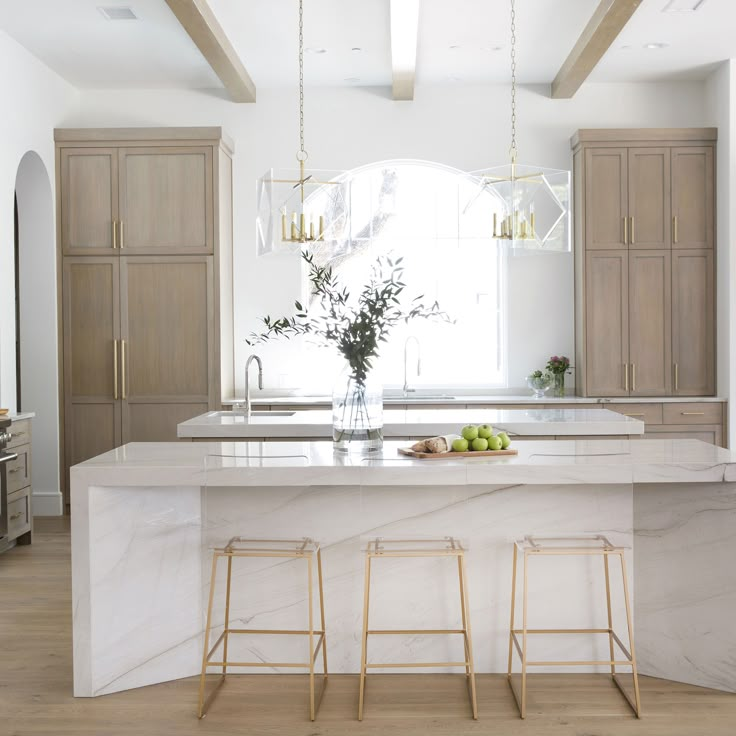 a kitchen with marble counter tops and wooden stools in front of an island that's surrounded by cabinets