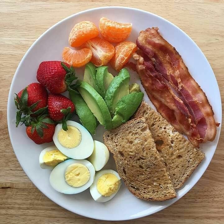 a white plate topped with eggs, bacon and fruit