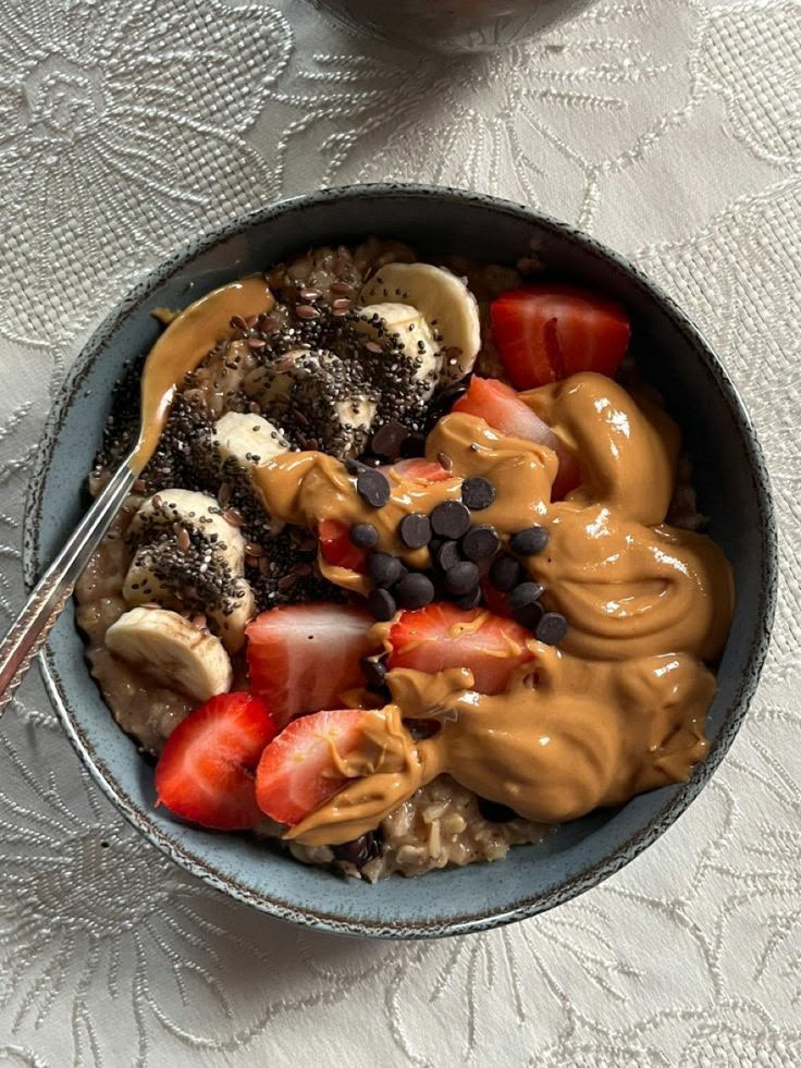 a bowl filled with oatmeal and fruit on top of a white tablecloth