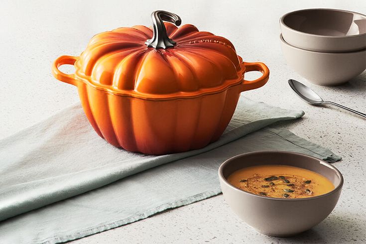 a bowl of soup next to a pumpkin shaped pot