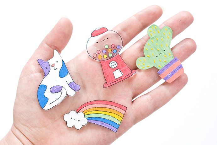 a person's hand holding several small magnets in the shape of animals and cactuses