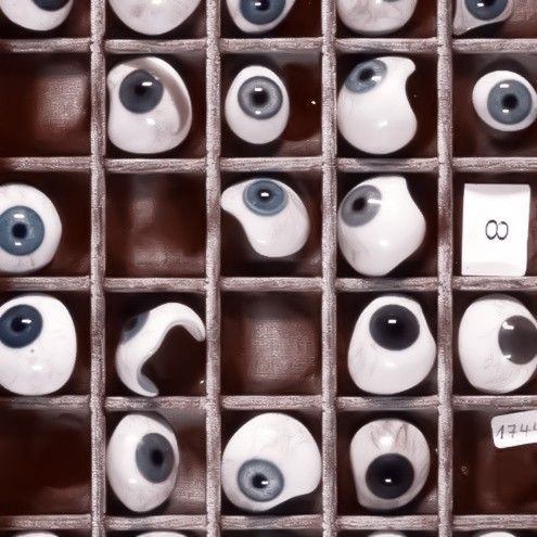 an assortment of white and black eyeballs are displayed in a box on the wall