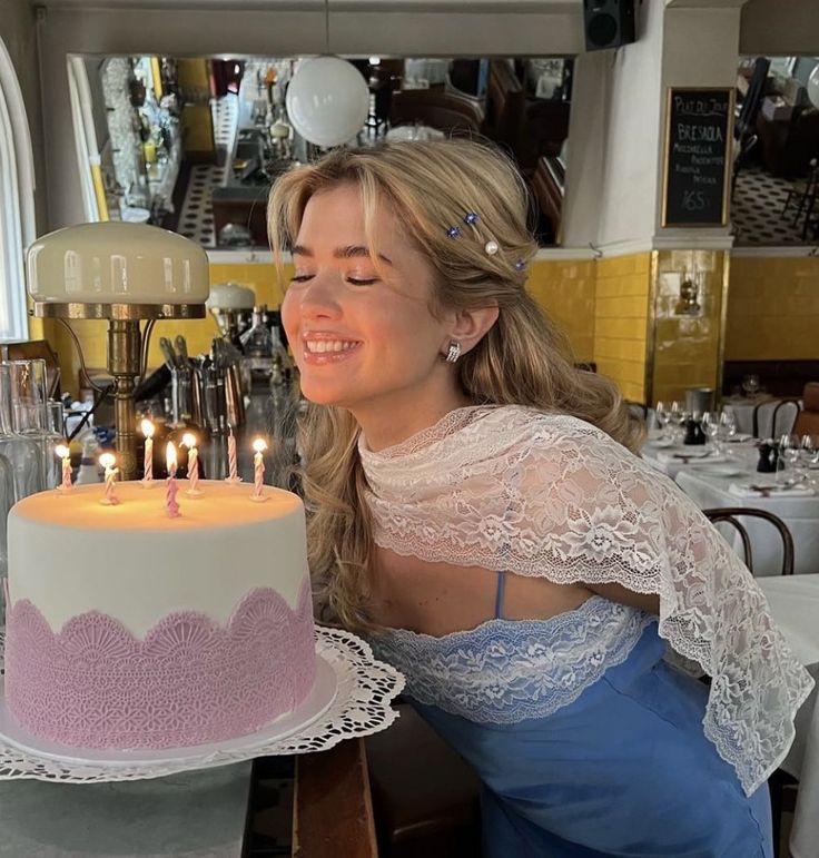 a woman sitting in front of a cake with lit candles