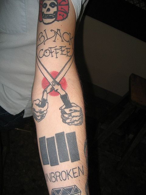 a man with tattoos on his arm holding a knife and fork in the other hand