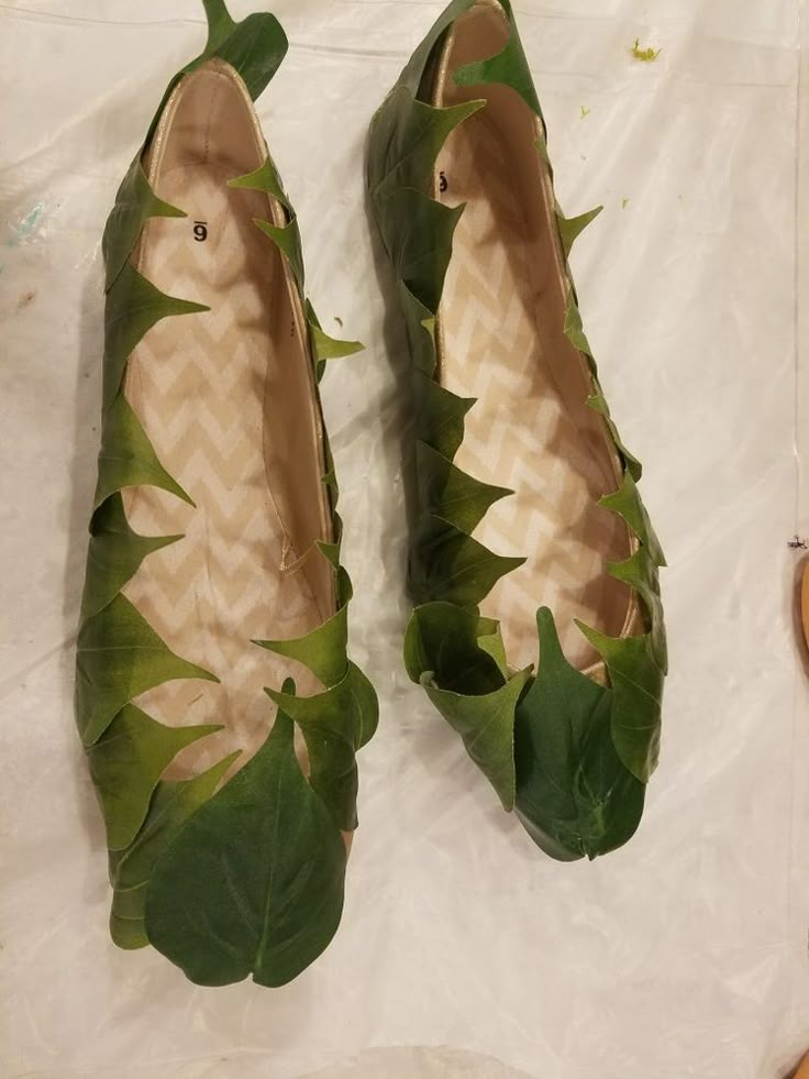 two pairs of shoes with leaves on them sitting on top of a sheet of paper