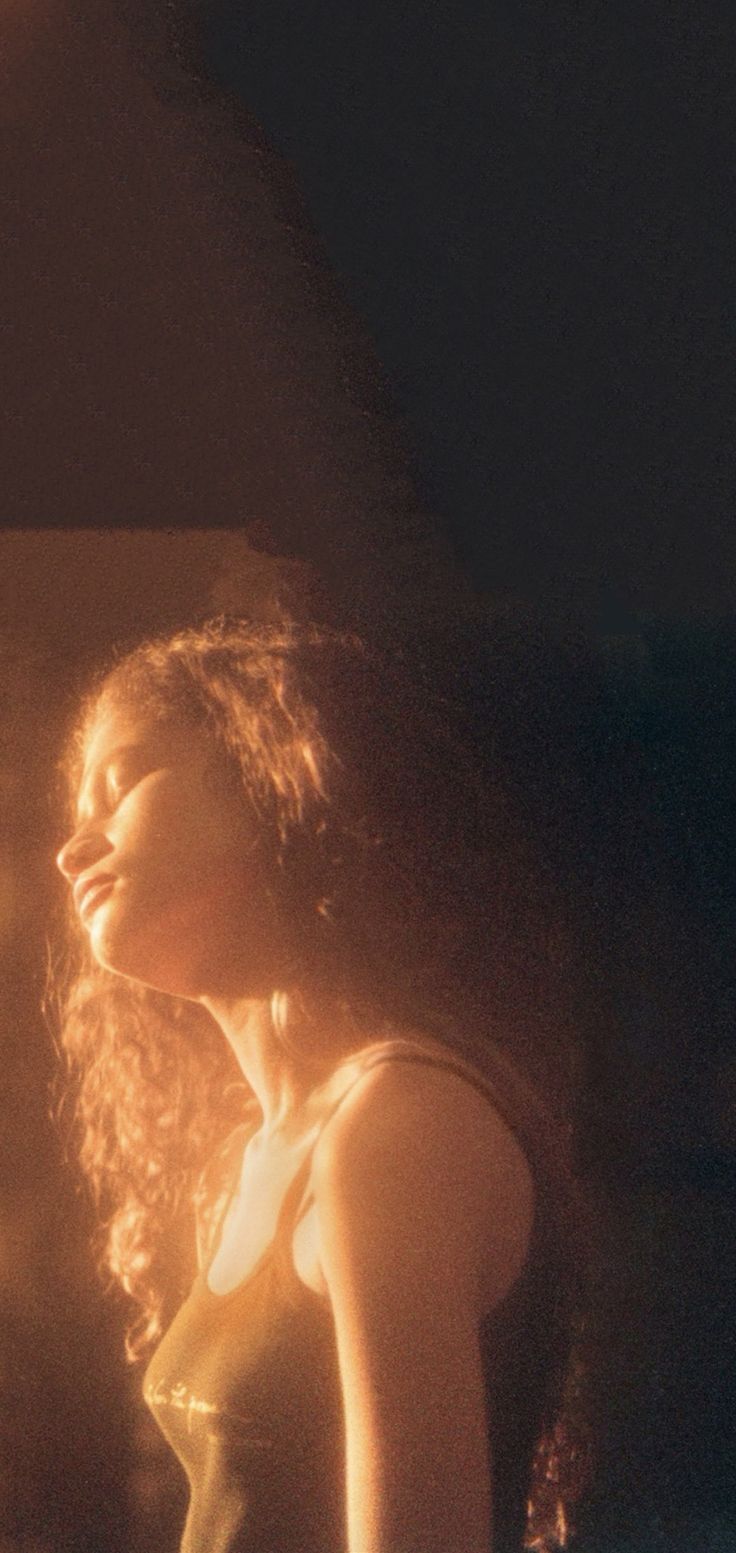 a woman with long hair standing in front of a fire hydrant and looking up at the sky