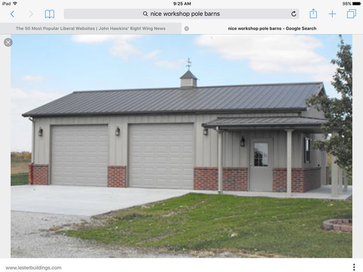 a two car garage sits in front of a brick building with a metal roof and chimney