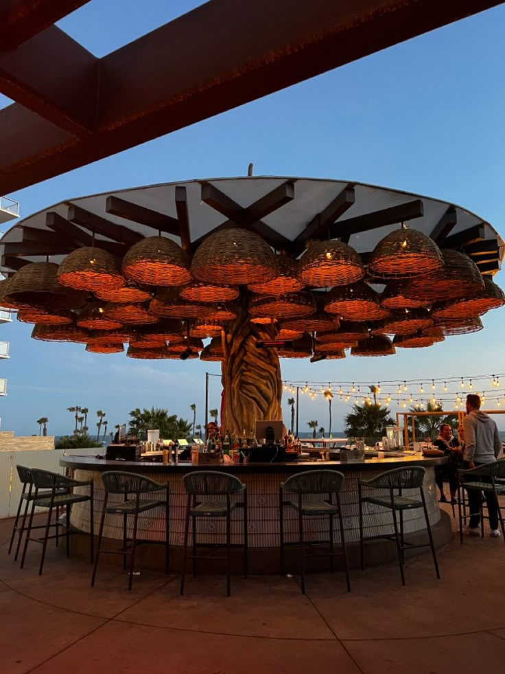 an outdoor dining area with lights hanging from the ceiling