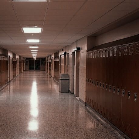 an empty hallway with many lockers and lights