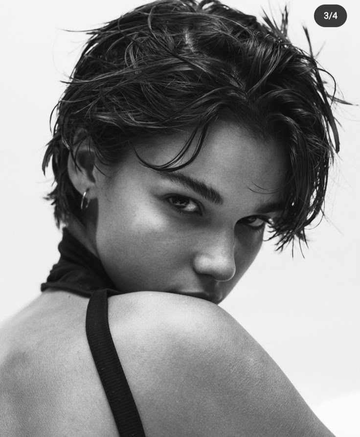 a black and white photo of a woman with her back to the camera, wearing a halter top