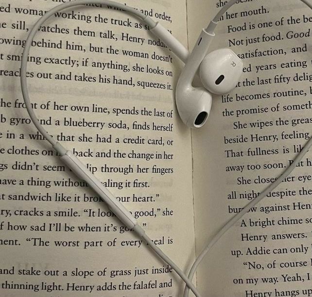 an open book with headphones laying on top of each other in the shape of a heart