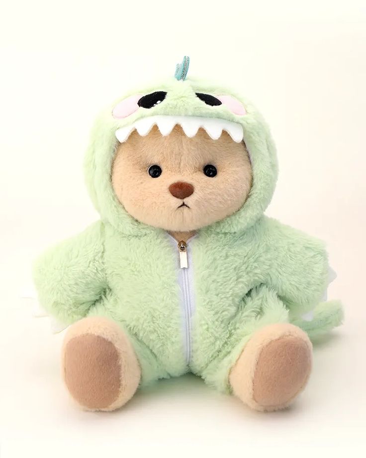 a teddy bear with a green monster costume on it's face and mouth, sitting in front of a white background