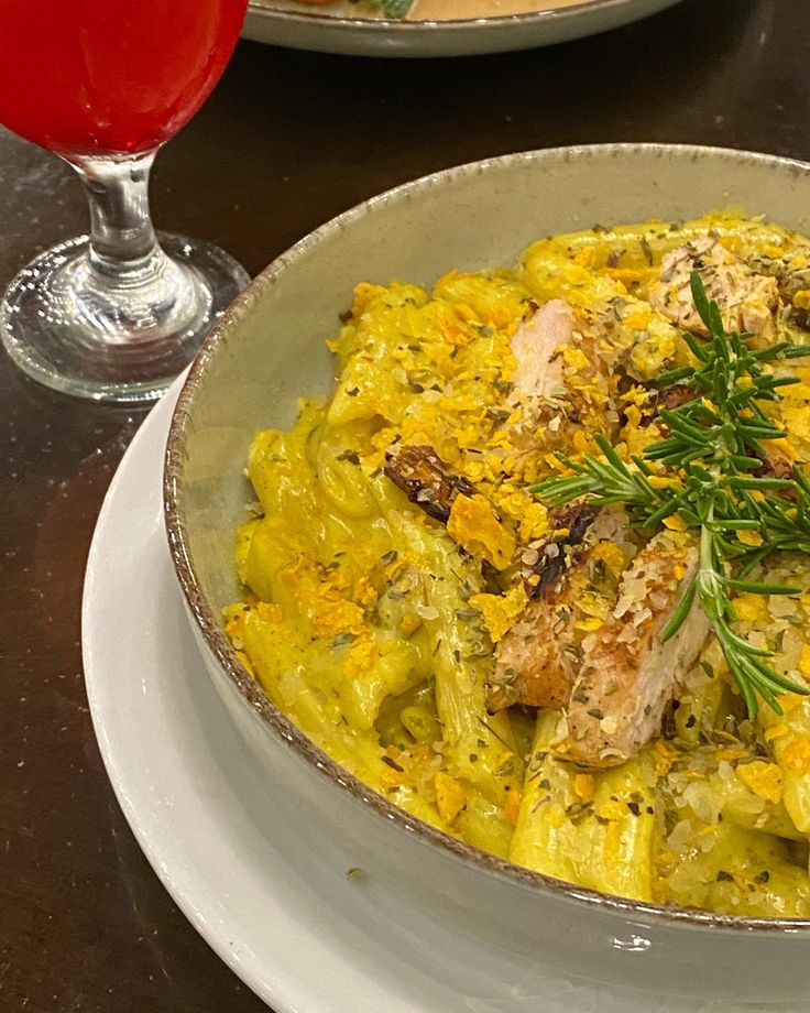 a bowl filled with food on top of a table next to a glass of wine