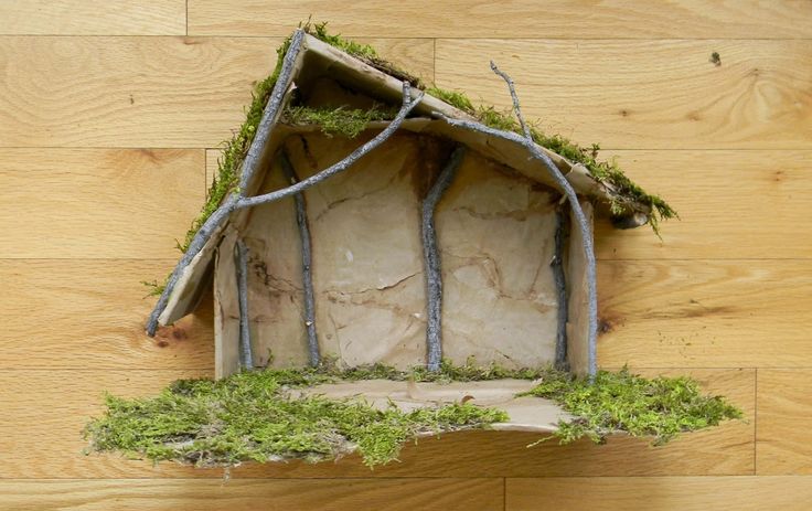 a house made out of wood with moss growing on the roof and windows above it