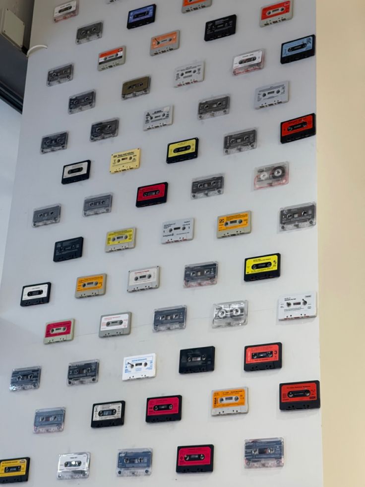 there are many cassettes on the wall and one is red, yellow, black and white