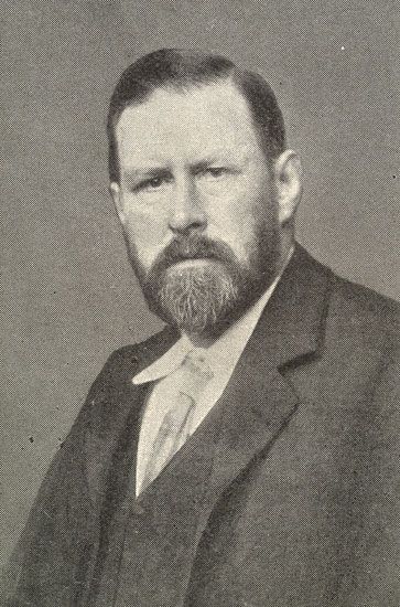 an old black and white photo of a man with a beard wearing a suit jacket