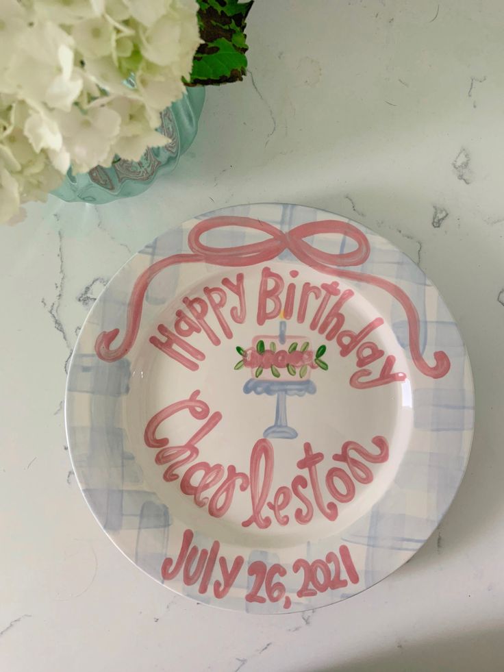 a happy birthday plate on a table next to flowers