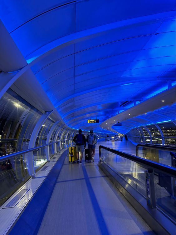 two people are walking down an escalator with their luggage in the foreground