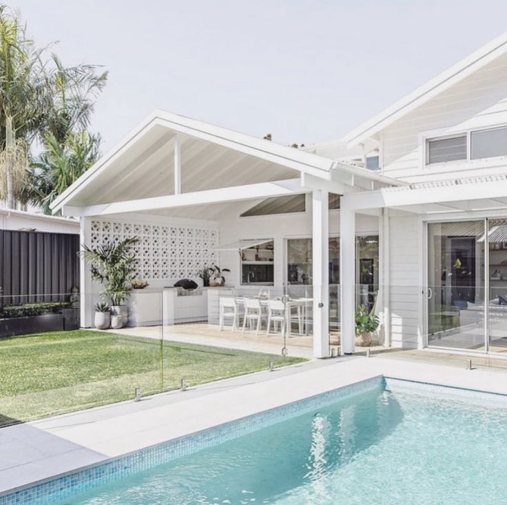 a house with a pool in front of it and an outdoor dining area on the other side