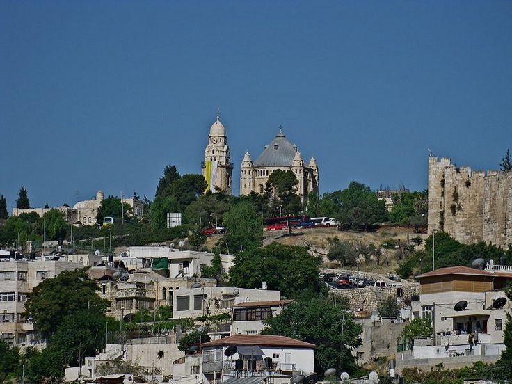 an old city sits on top of a hill in the middle of trees and rocks