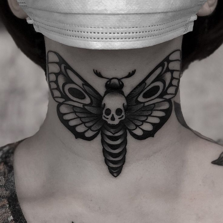 a woman with a skull and butterfly tattoo on her neck