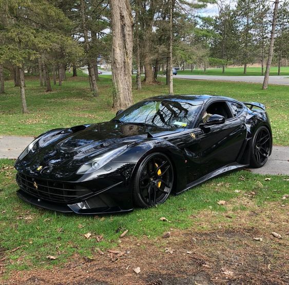 a black sports car parked on the side of a road in front of some trees