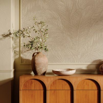 a vase with some flowers sitting on top of a wooden cabinet in front of a wall