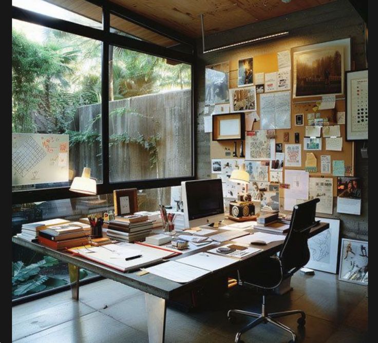 an office with lots of papers and pictures on the wall, along with a large window