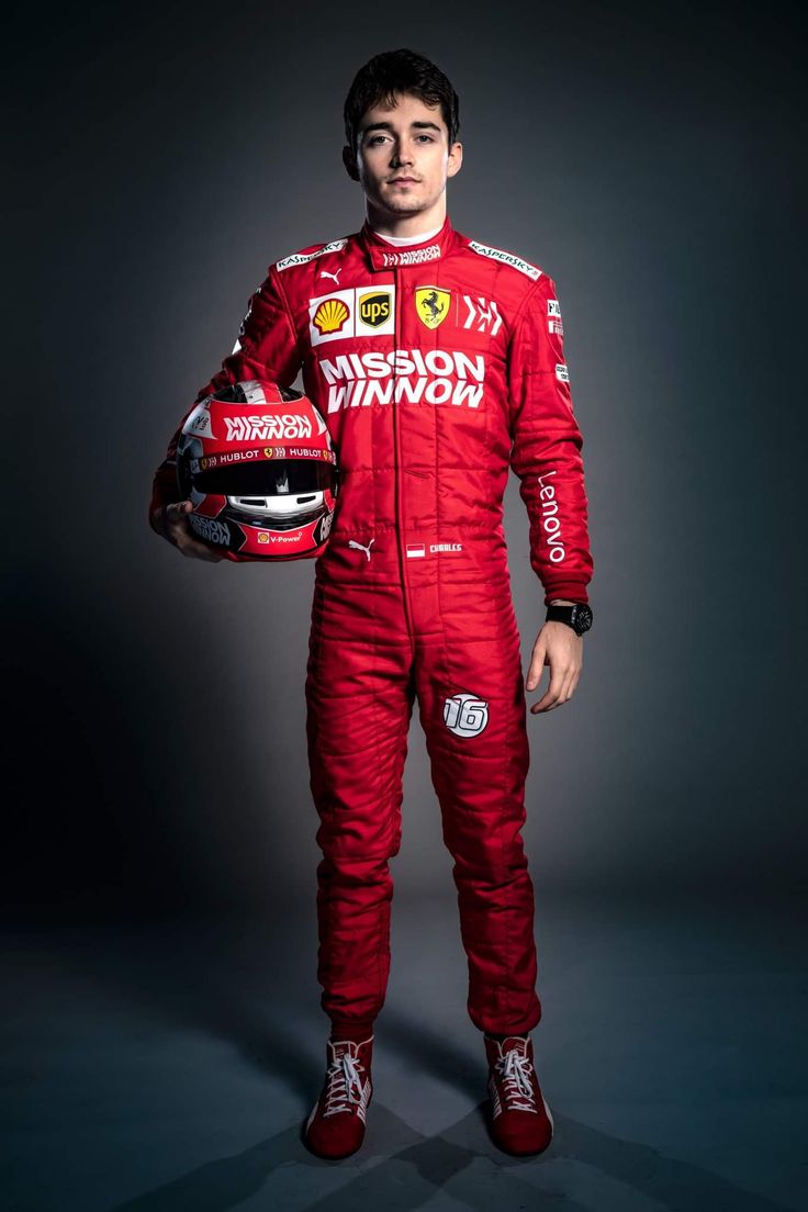 a man in a racing suit holding a helmet