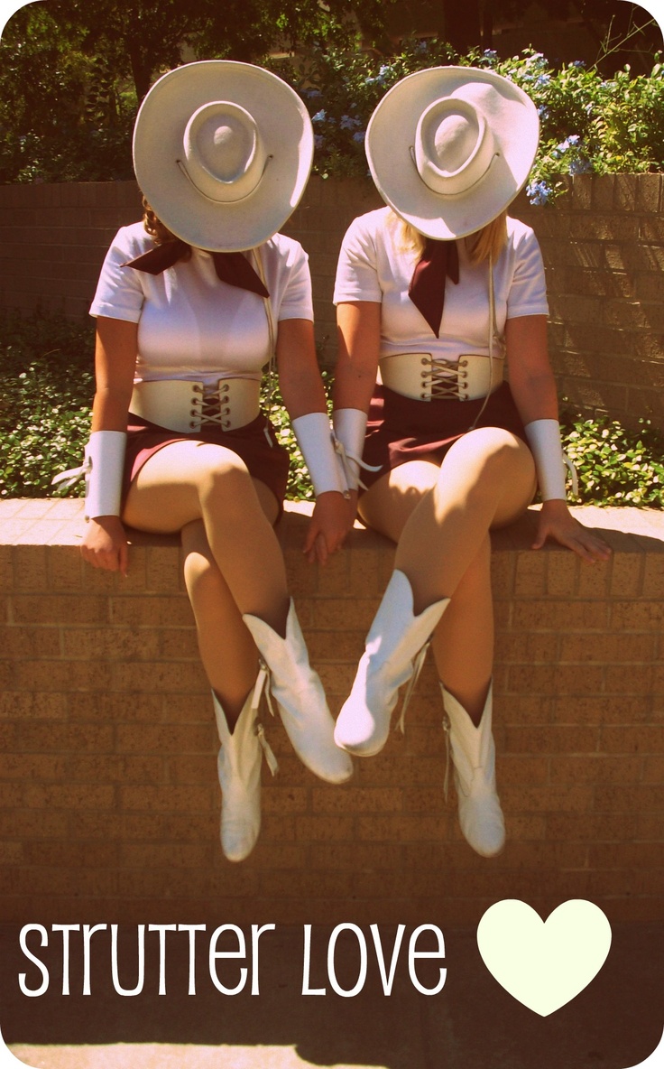 two women wearing white hats sitting on top of a brick wall next to each other