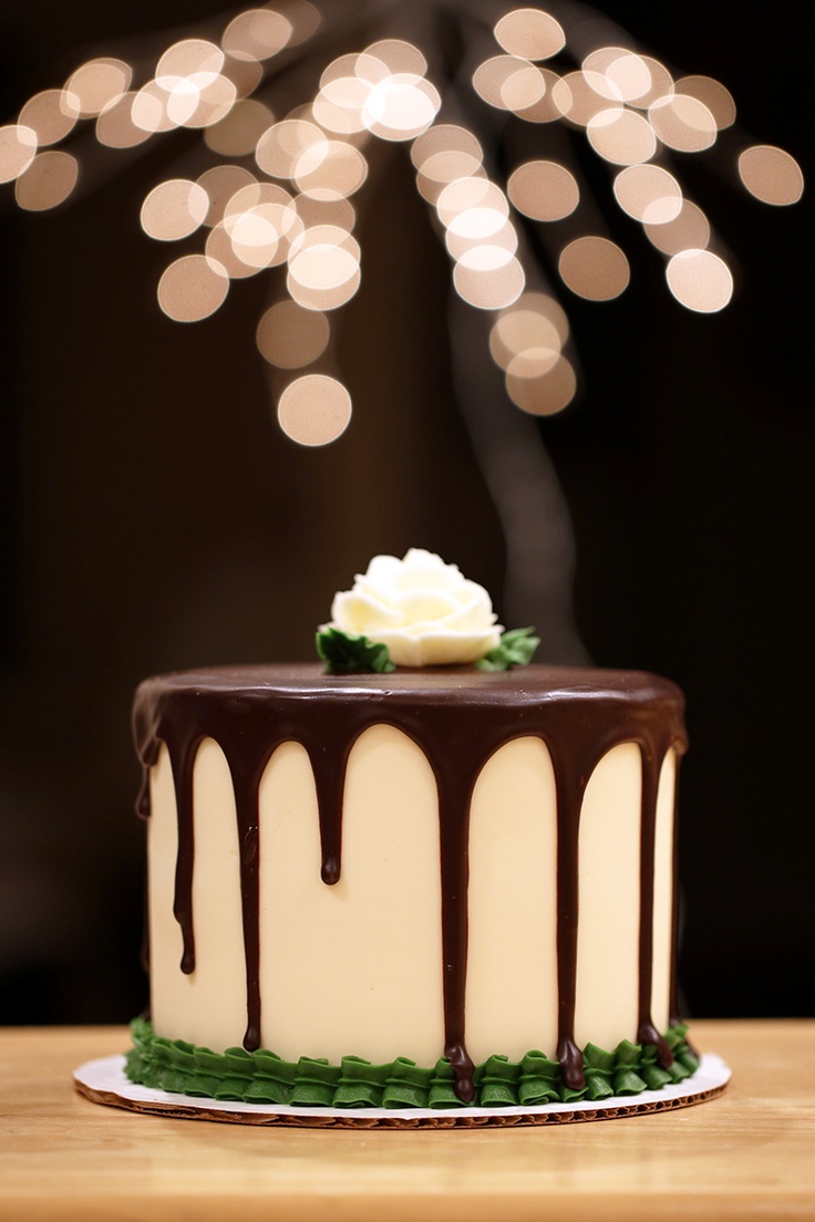 a cake with chocolate icing and white flowers on top is sitting on a table