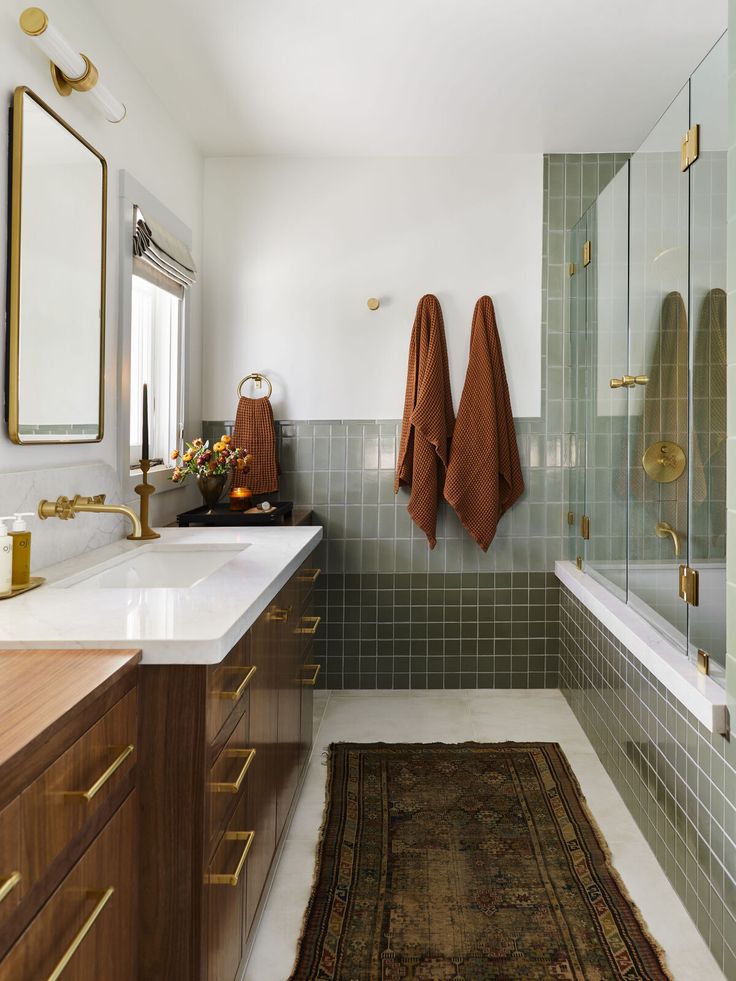 a bathroom with two towels hanging on the wall and a rug in front of it