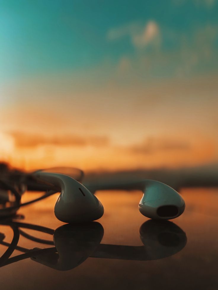 two white ear buds sitting on top of a table next to a blue and orange sky