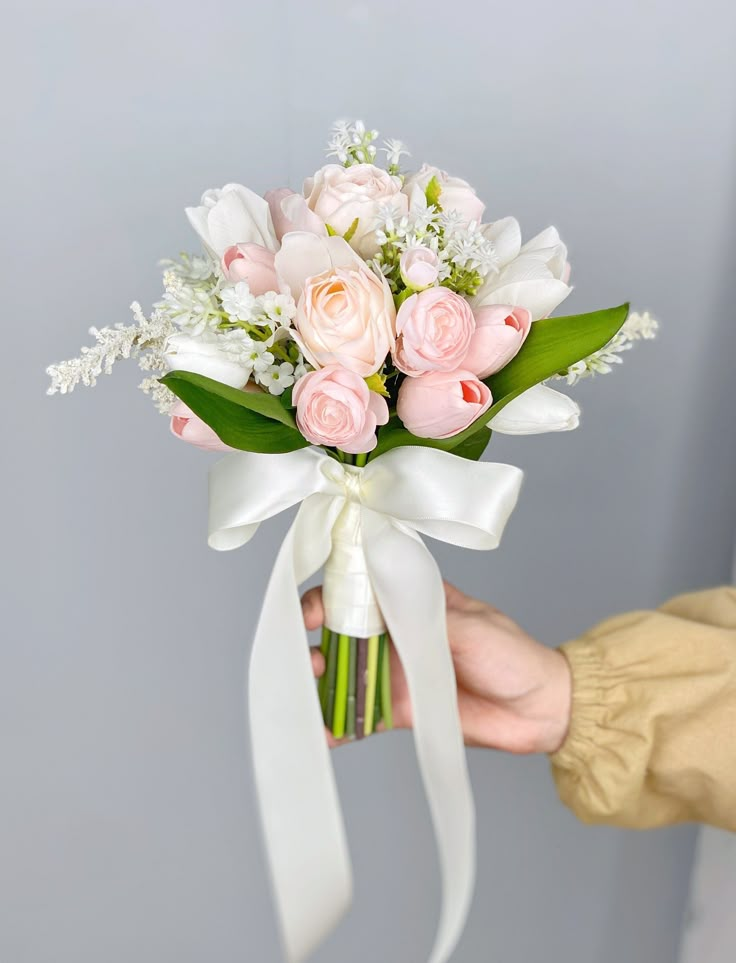 a person holding a bouquet of white and pink flowers