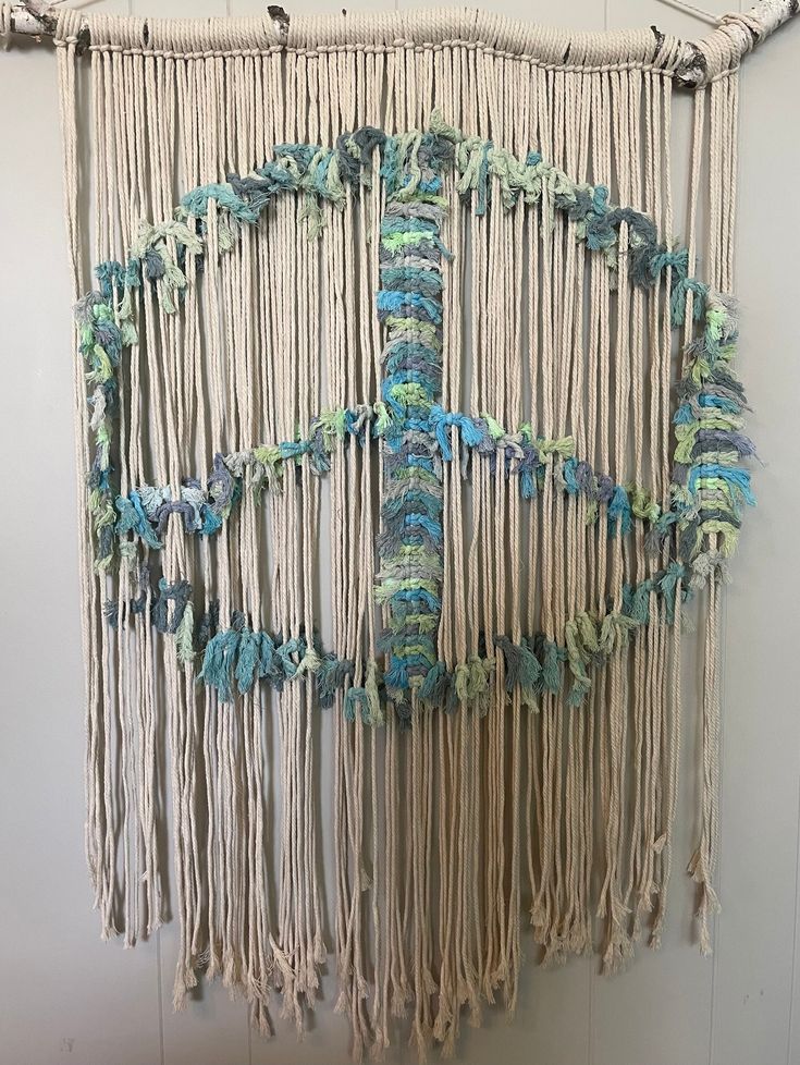 a wall hanging made out of macrame beads and yarn with blue, green and white colors