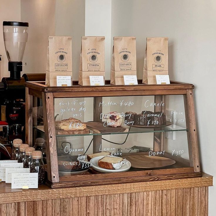 a bakery display case filled with cakes and pastries on top of a wooden counter