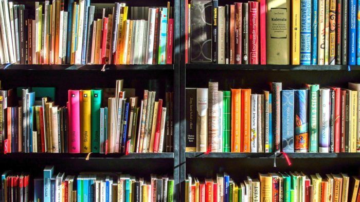 a book shelf filled with lots of colorful books next to a wall full of books