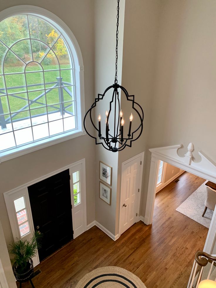 an overhead view of a living room and entryway with wood floors, arched windows, and chandelier