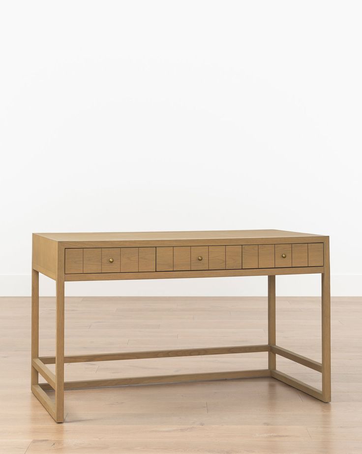 a wooden table with three drawers sitting on top of a hard wood floor next to a white wall