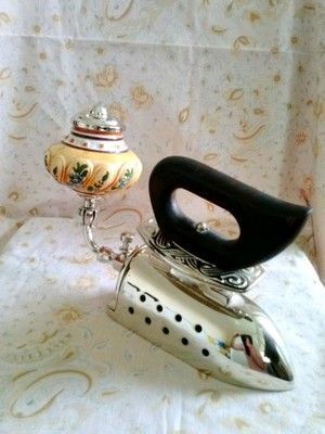 an old fashioned tea kettle sitting on top of a stand next to a decorative vase