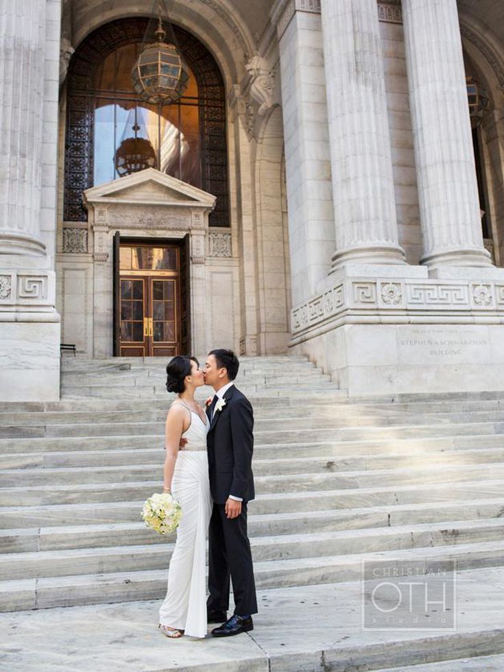 a bride and groom standing in front of a large building with columns on each side