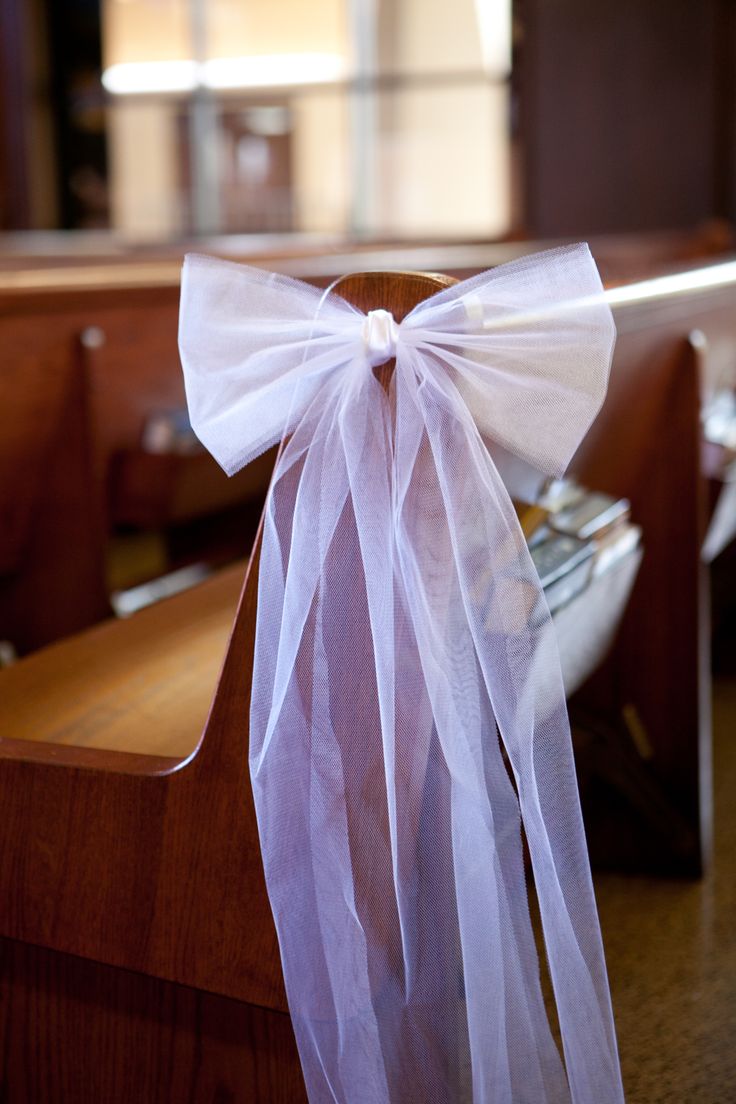 a white ribbon tied to the back of a church pew