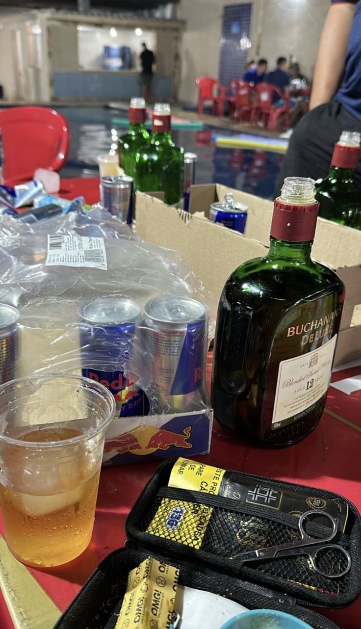 there are many bottles and containers on the table with drinks in them, along with other items