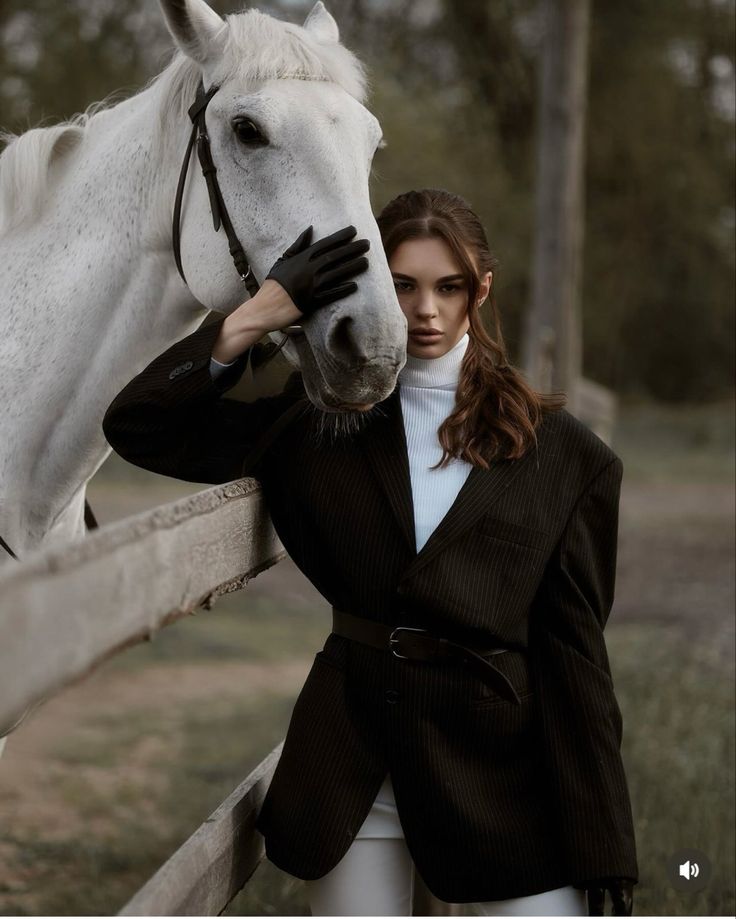 a woman standing next to a white horse