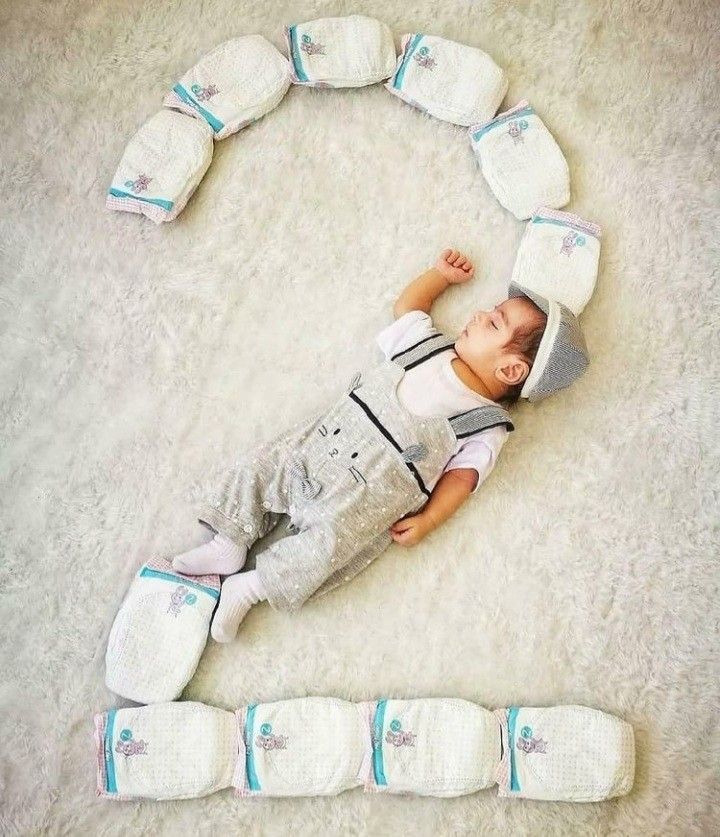 a baby laying on its back next to several diapers