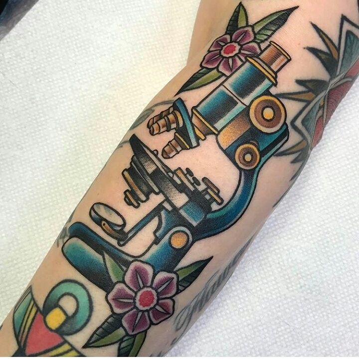 an arm with a tattoo on it that has a machine and flowers in the background