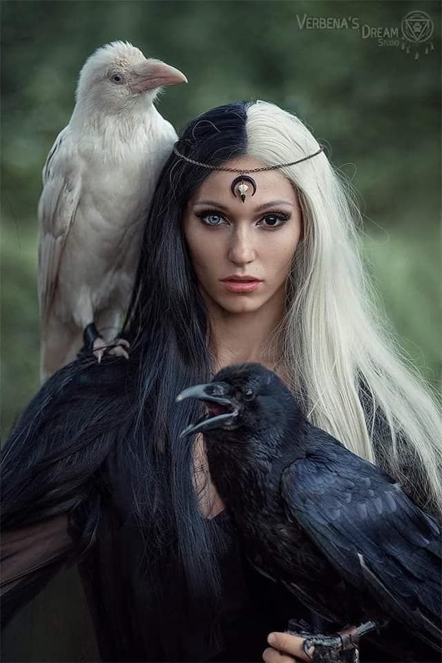 a woman with long hair and two crows on her shoulder, both wearing black makeup